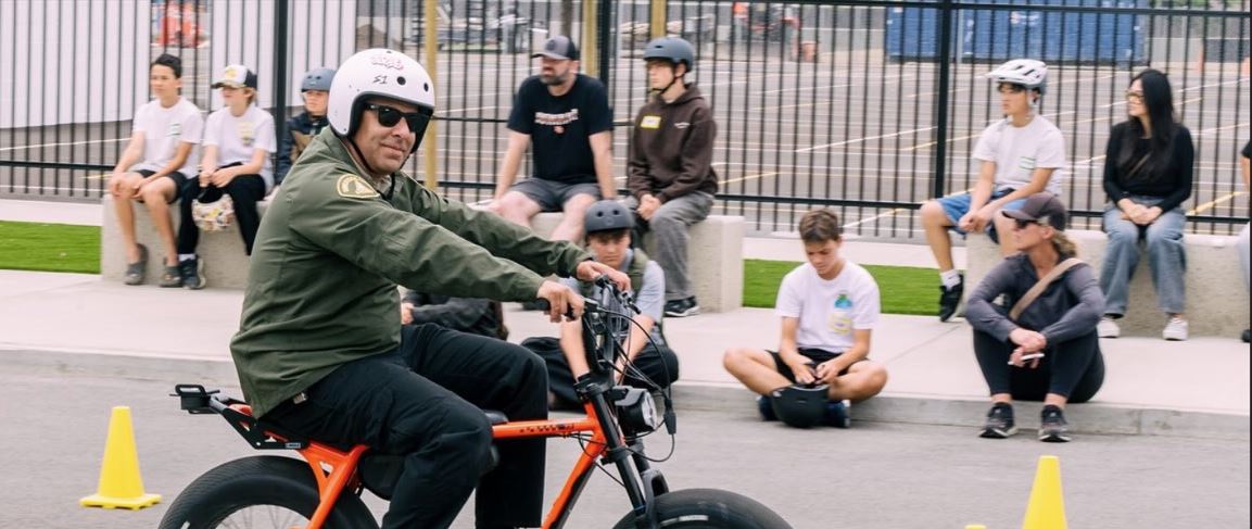 A VoltVerified instructor in a white helmet demonstrating eBike control on a coned course while student riders watch