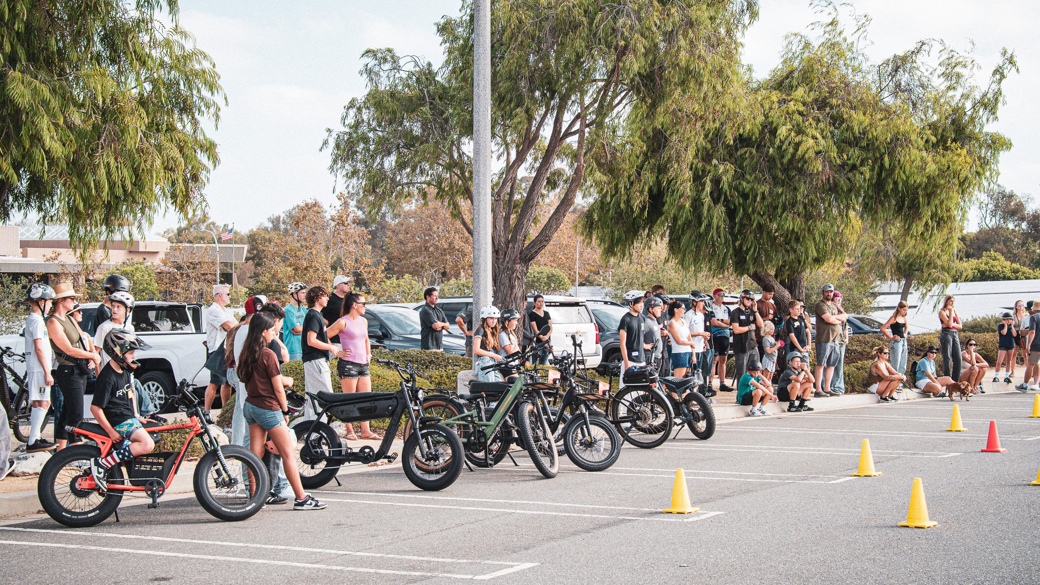 Young riders and adults gathered with their bikes beside a coned community training area