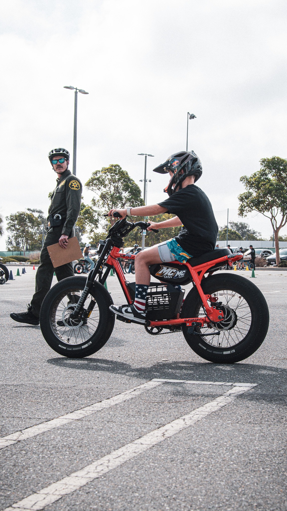 A deputy observing a helmeted young rider during a controlled eBike training exercise