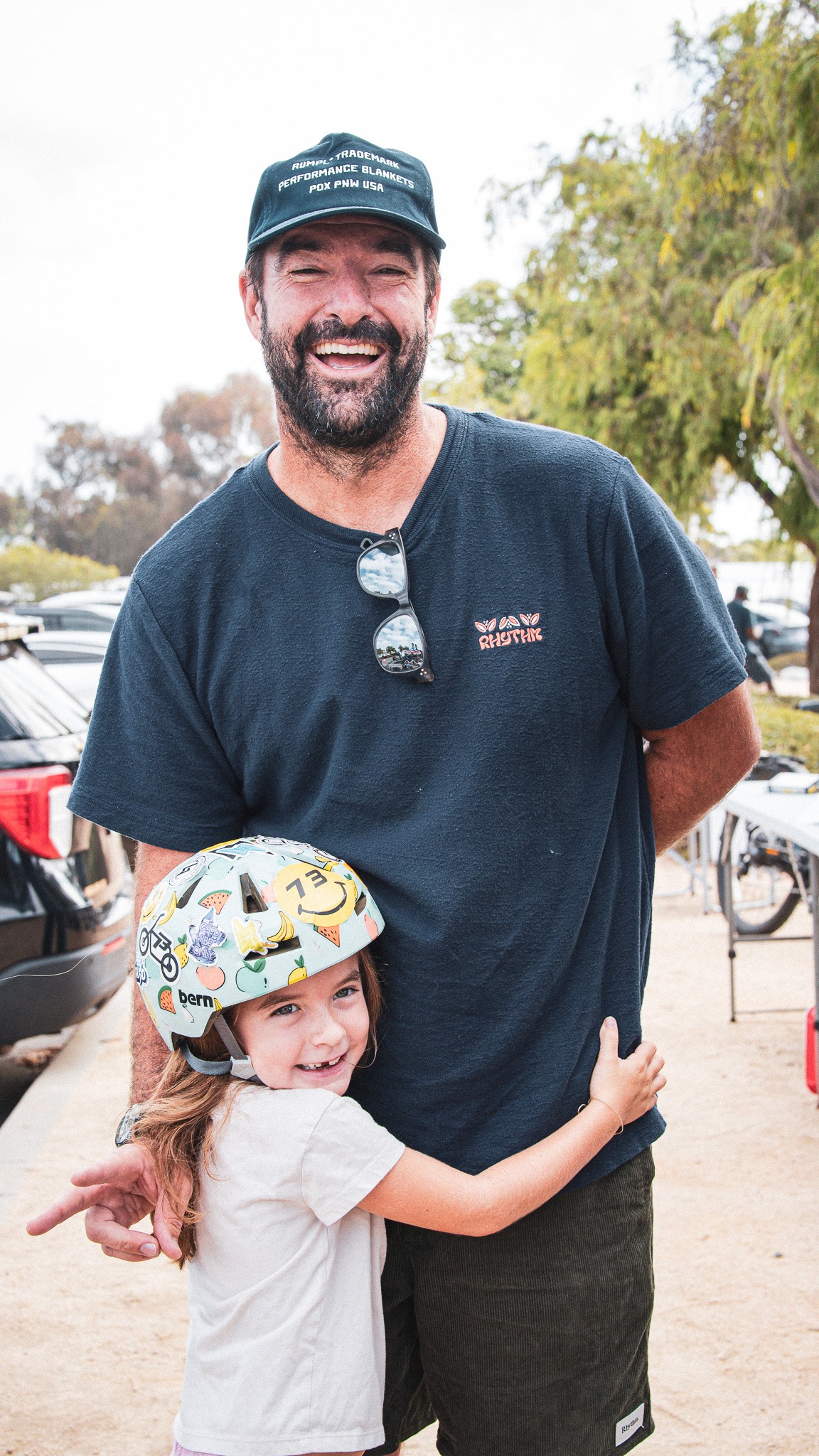 An adult and a helmeted young rider smiling together at an outdoor training event