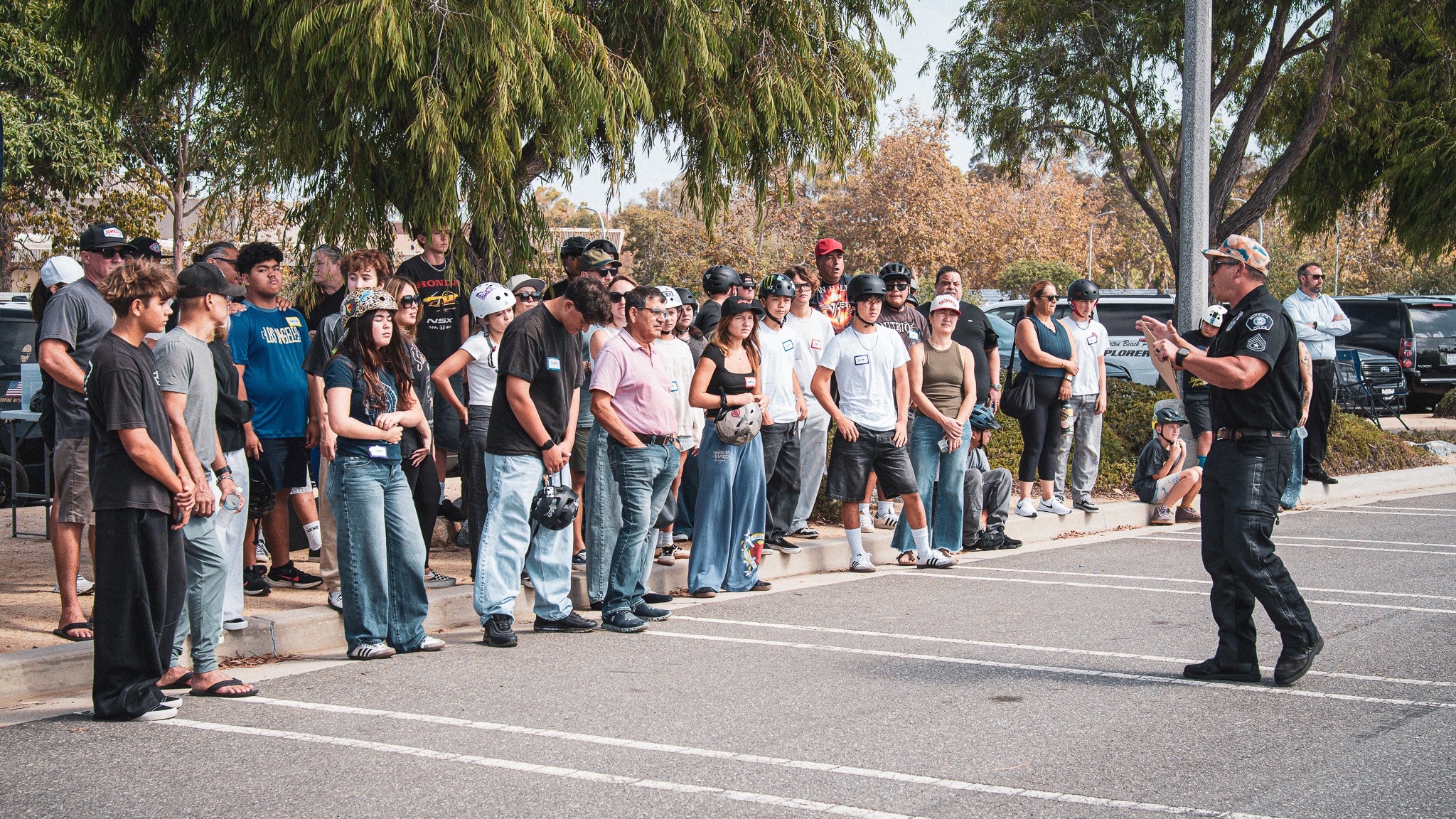 An officer briefing adults and young riders together at an outdoor training event